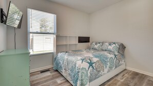 Ein Schlafzimmer mit einem Bett, einem Fenster mit Jalousien, einem Deckenventilator und einem grünen Schrank.