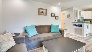 Ein Wohnzimmer mit einer Couch, einem Couchtisch und einer Küche im Hintergrund.