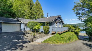 A two-story house with a garage, a covered porch, and a view of a lake. - Waterfront Union Getaway w/ Ocean & Mtn Views (Union)