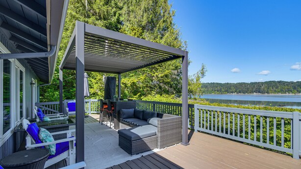 A covered outdoor deck with a sofa and chairs, a grill, and a view of a lake. - Waterfront Union Getaway w/ Ocean & Mtn Views (Union)