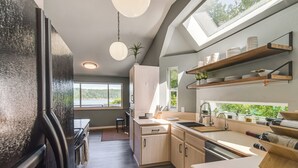 A modern kitchen with a large window, built-in shelves, and a refrigerator. - Waterfront Union Getaway w/ Ocean & Mtn Views (Union)