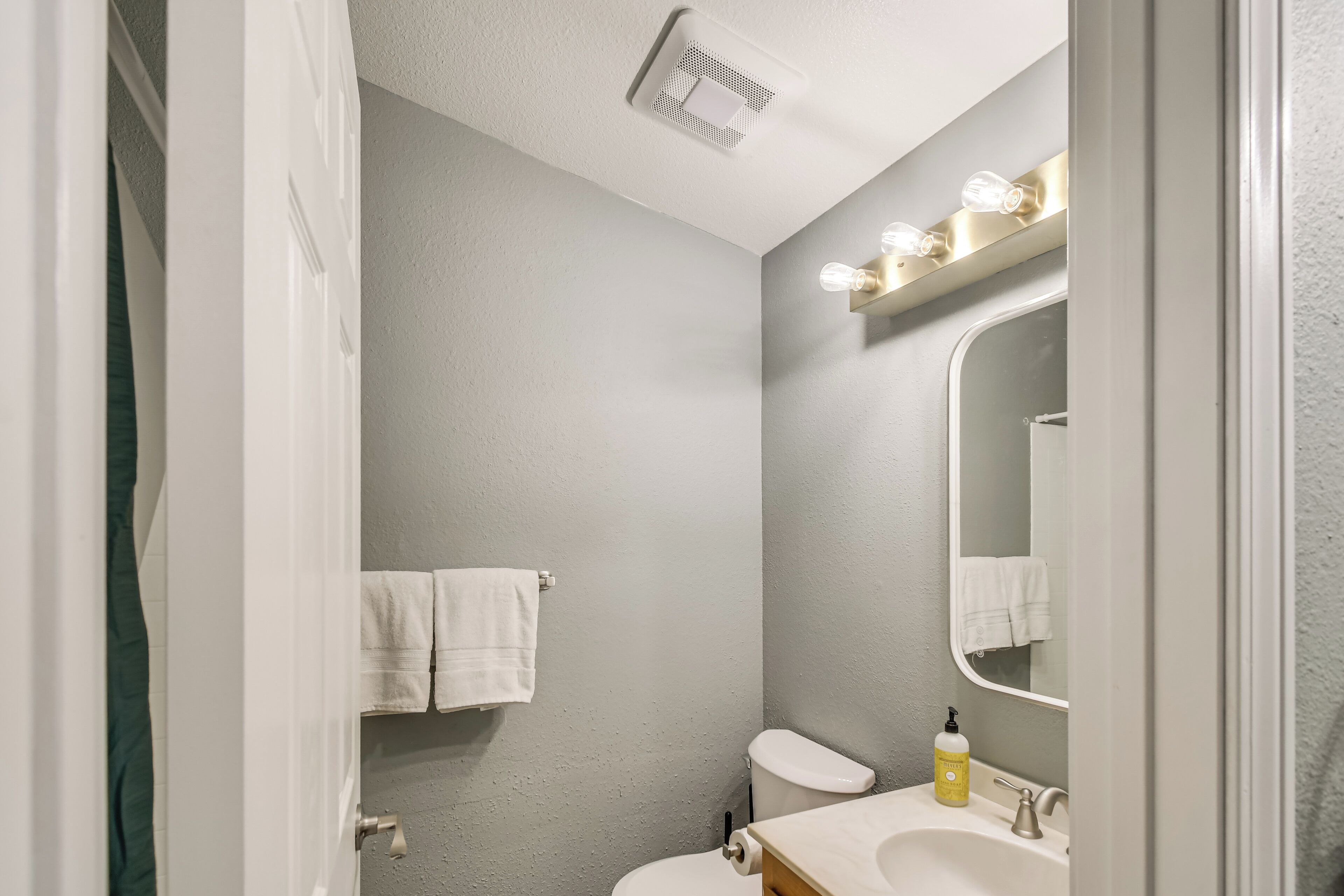 A bathroom with a toilet, sink, and mirror.