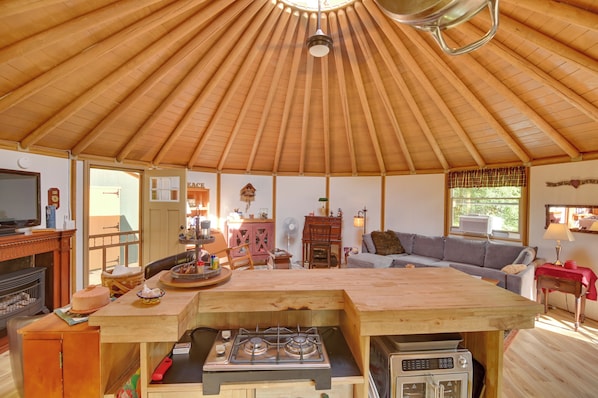 A cozy interior with a wooden ceiling, a dining area, a sofa, and a kitchenette.