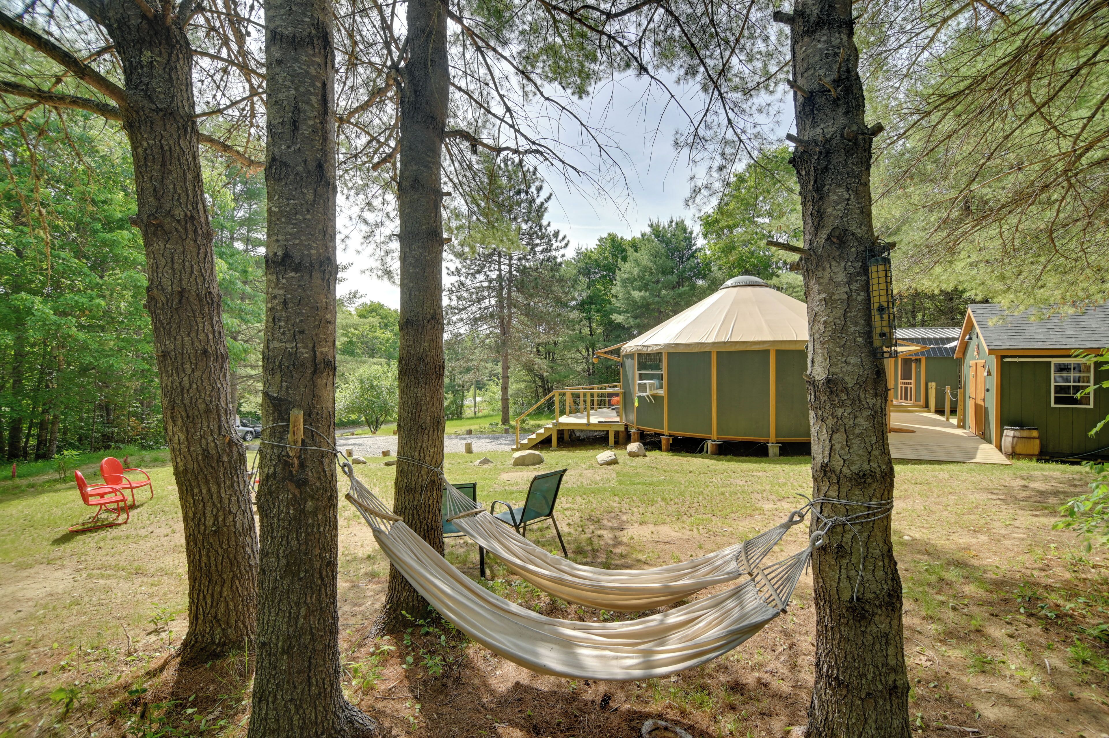 A hammock between trees, a small outdoor seating area, and a cabin with a porch.