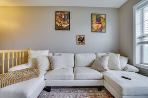 A living room with a white sofa, a wooden headboard, and a window with blinds. - Spacious & Quiet Townhome In the Twin Cities (Roseville)