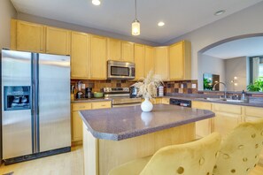 A modern kitchen with wooden cabinets, stainless steel appliances, a granite countertop, and a vase with dried flowers. - Spacious & Quiet Townhome In the Twin Cities (Roseville)