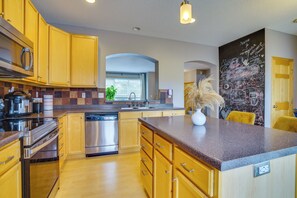 A modern kitchen with wooden cabinets, stainless steel appliances, and a granite countertop. - Spacious & Quiet Townhome In the Twin Cities (Roseville)