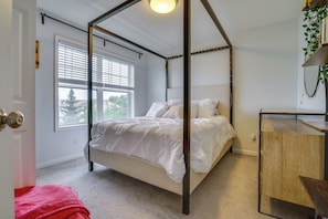 A four-poster bed with a wooden frame, a bedside table, a window with blinds, and a plant on a shelf. - Spacious & Quiet Townhome In the Twin Cities (Roseville)