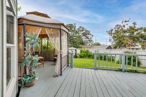Eine überdachte Terrasse mit Sitzgelegenheit, einem Blumentopf und Blick auf den Garten.