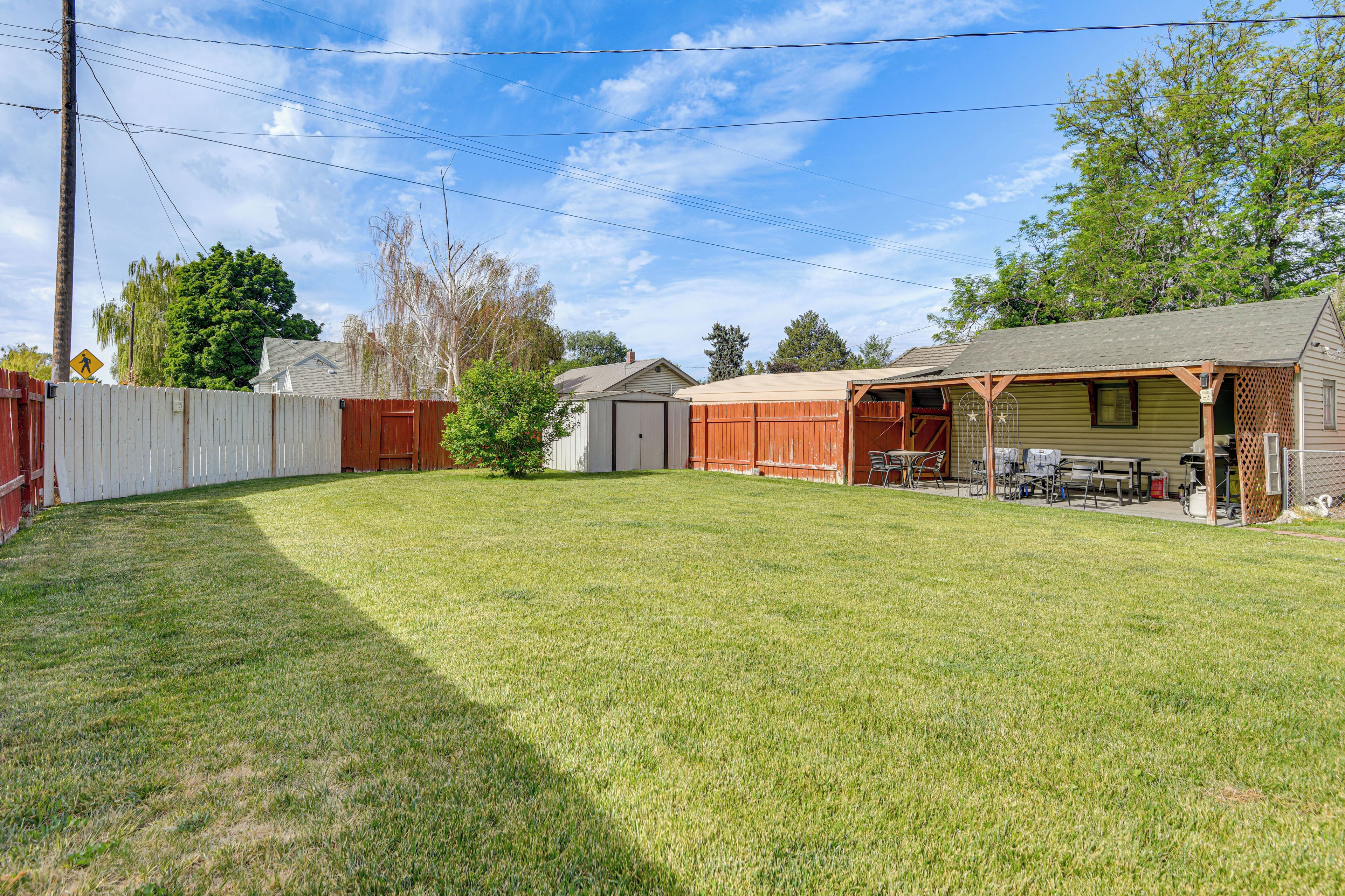 A backyard with a fenced area, a shed, and a garage.