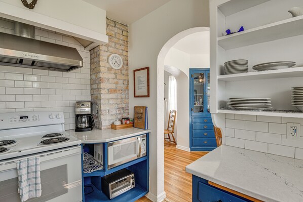 A kitchen with a white stove, a coffee maker, and a microwave on a blue shelf.