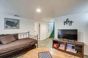 Une chambre à coucher avec un lit, une télévision, un jeu d’échecs et un mur orné d’une carte et du mot « jeu ».