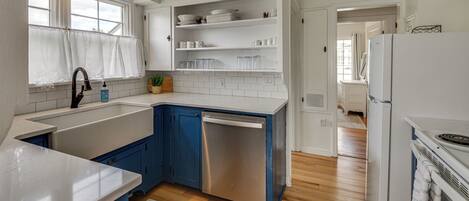 A kitchen with white cabinets, a dishwasher, and a refrigerator.