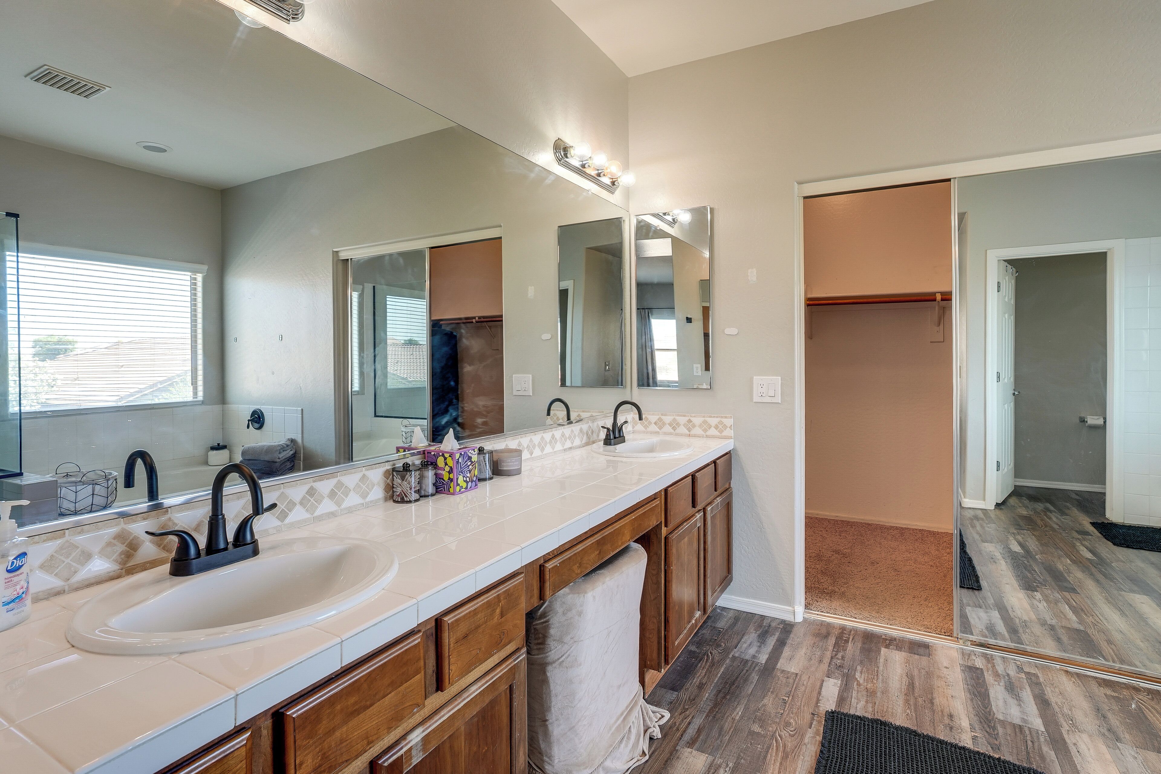 A bathroom with a double sink, large mirrors, and a walk-in closet.
