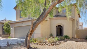A residential building with a garage, a driveway, and a landscaped front yard with a tree and plants. - Modern Family Oasis Pool Game Room (Maricopa)