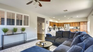 A modern living room with a sectional sofa, a coffee table, and a console table with plants. - Modern Family Oasis Pool Game Room (Maricopa)