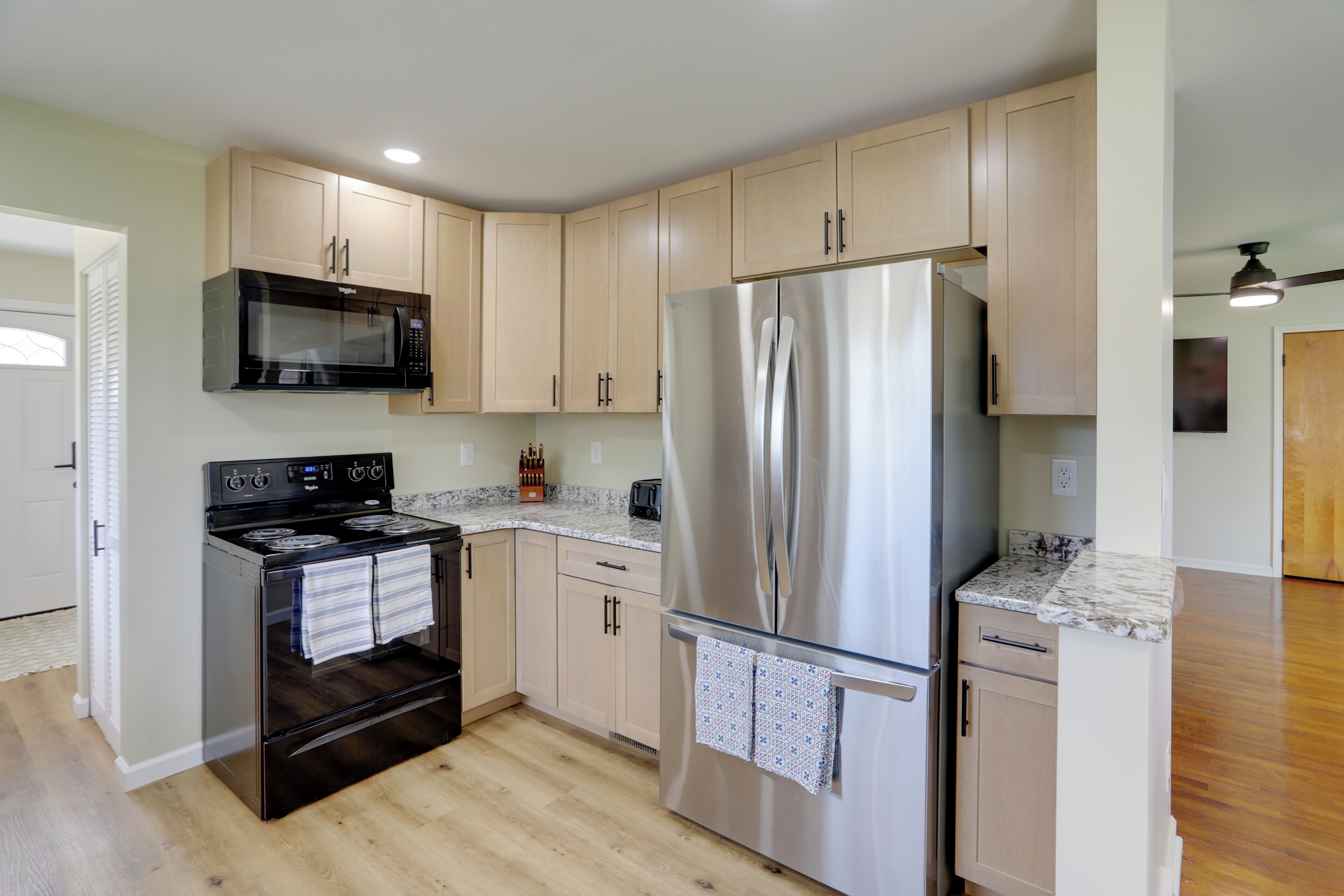A kitchen with a stainless steel refrigerator, a microwave, and an oven.
