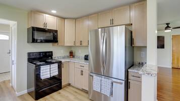 A kitchen with a stainless steel refrigerator, a microwave, and an oven.