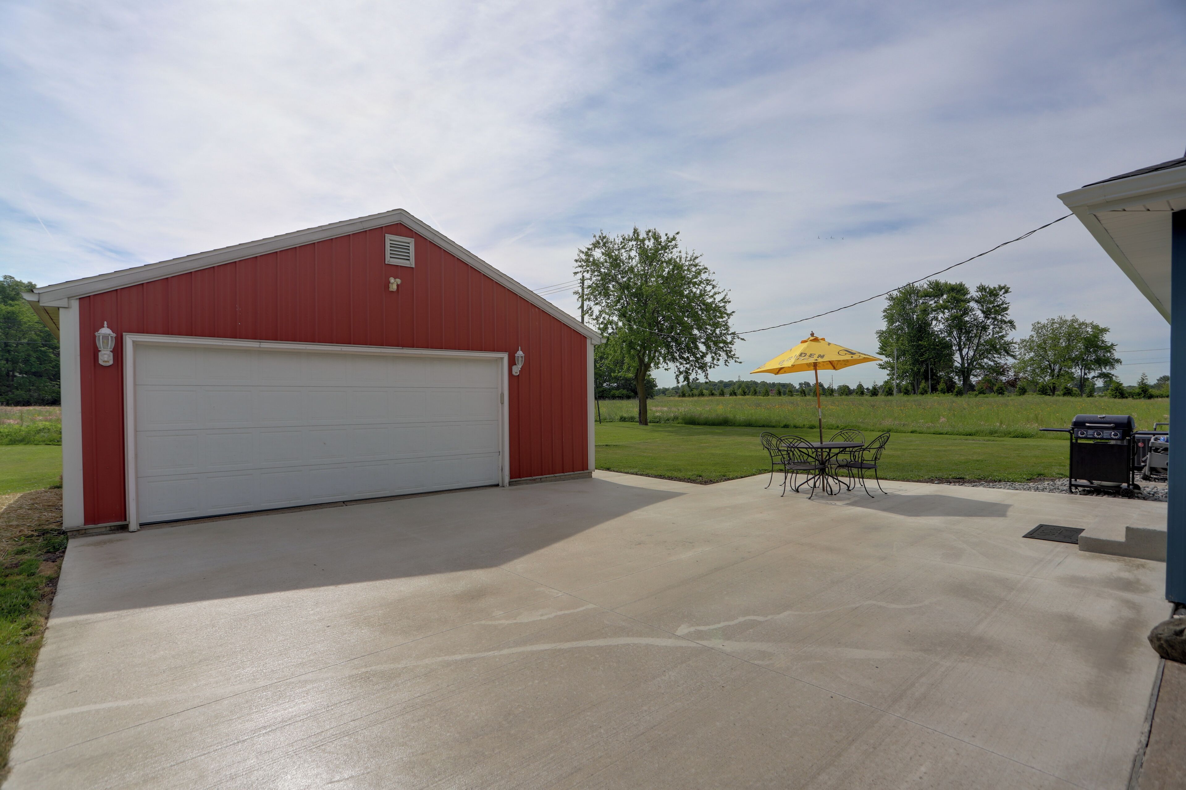A red garage with a white door, a concrete patio, and a yellow umbrella.