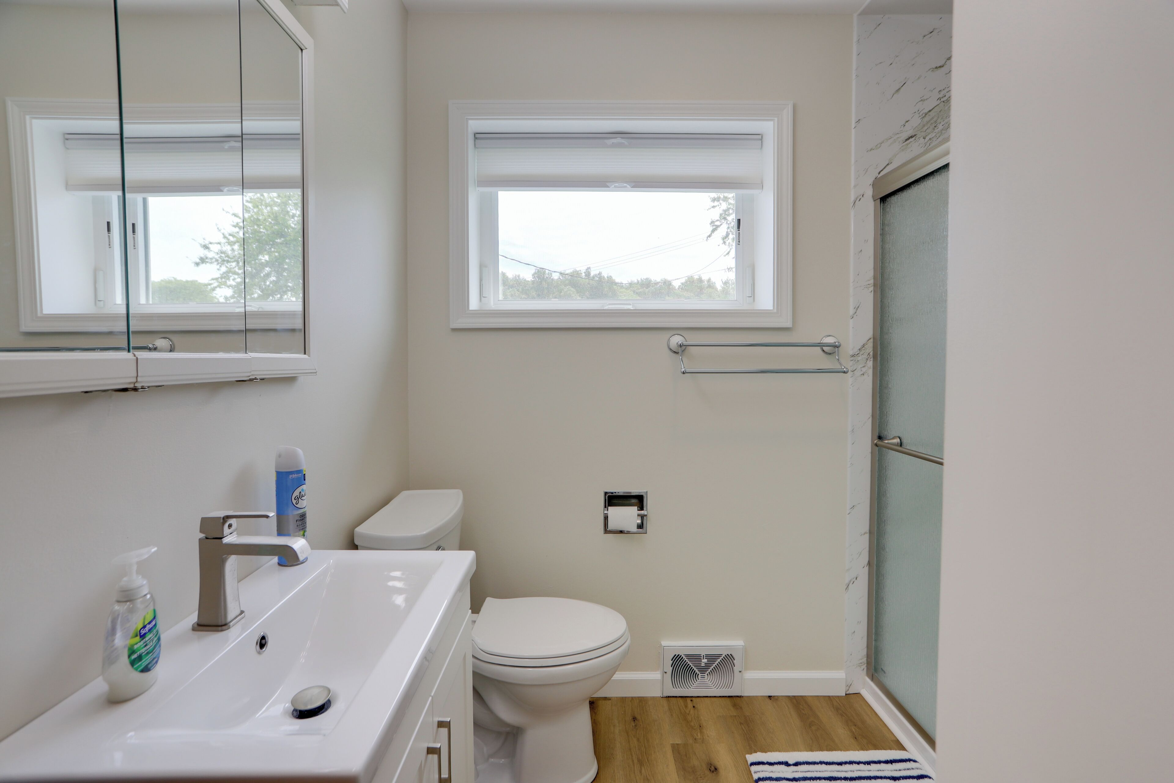 A bathroom with a white sink, toilet, and window.