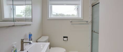 A bathroom with a white sink, toilet, and window.
