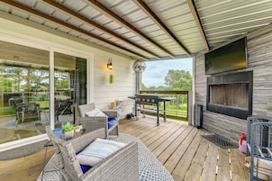 A covered outdoor area with wicker furniture, a grill station, and a TV mounted on the wall.