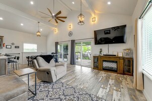A spacious living area with a ceiling fan, recessed lighting, a fireplace, and a large TV mounted on the wall.