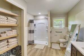A bathroom with a shower, toilet, and shelves with folded towels. - 2 Mi to Lake Hamilton: Countryside Gem w/ Fire Pit (Hot Springs)