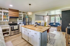 A modern kitchen with a central island, built-in appliances, and a dining area with a sofa and coffee table. - 2 Mi to Lake Hamilton: Countryside Gem w/ Fire Pit (Hot Springs)