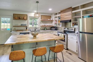 A modern kitchen with a central island, bar stools, built-in appliances, and wooden shelves. - 2 Mi to Lake Hamilton: Countryside Gem w/ Fire Pit (Hot Springs)