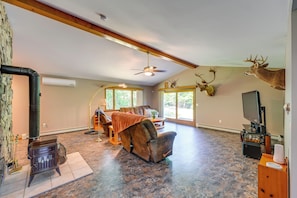 A spacious living room with a fireplace, leather recliner, mounted deer heads, and a television.