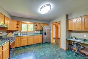 Una cocina con armarios de madera, un refrigerador de acero inoxidable, un fregadero y una estufa.