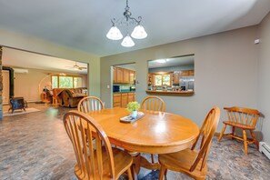 A dining area with a round wooden table, six chairs, and a chandelier. - Wooded Applegate Retreat w/ Private Trail Access (Carsonville)