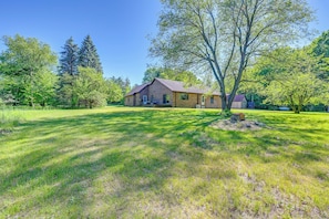 A house with a large lawn, a tree in the front yard, and a clear blue sky. - Wooded Applegate Retreat w/ Private Trail Access (Carsonville)