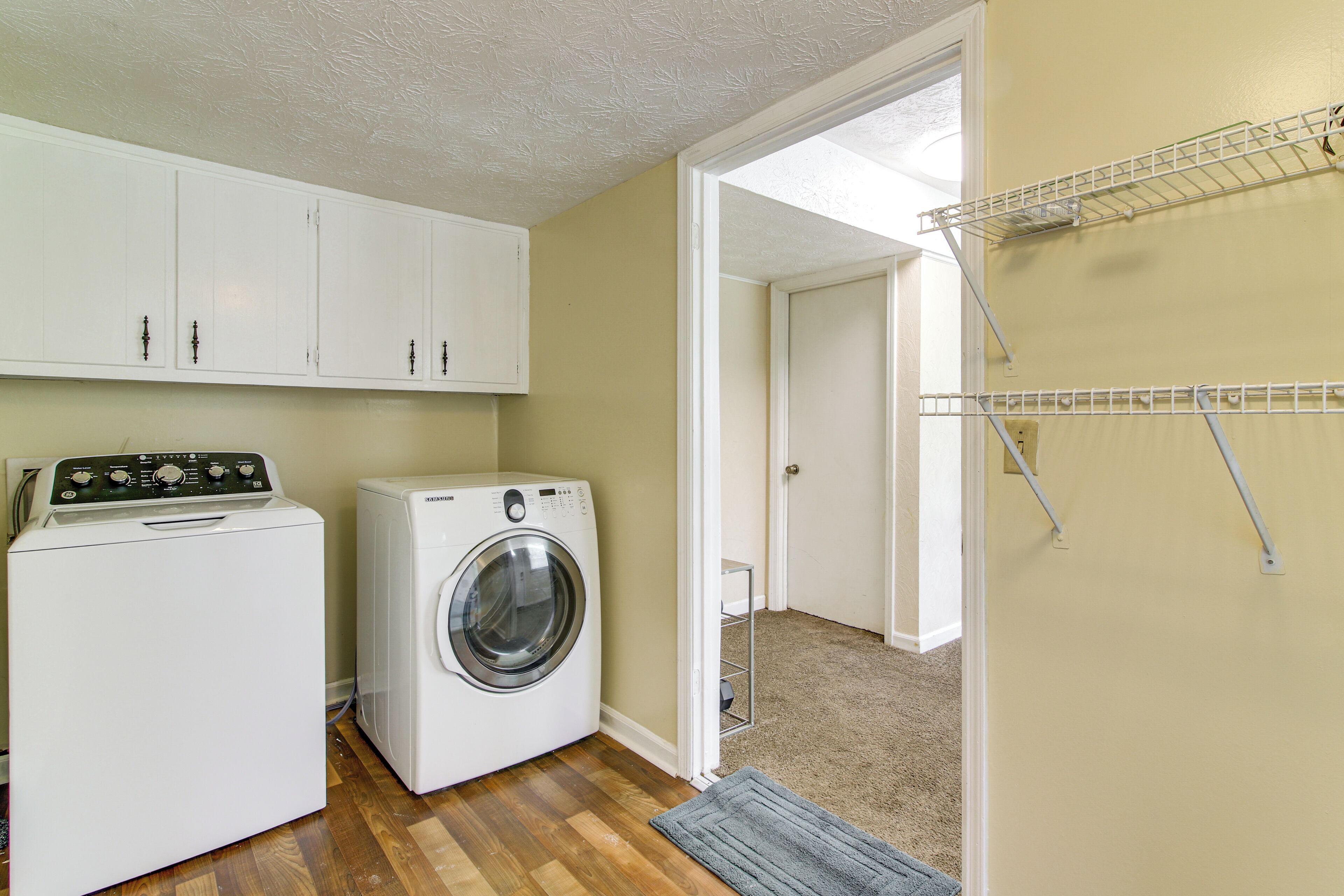 A laundry room with a washer and dryer, cabinets, and a drying rack.