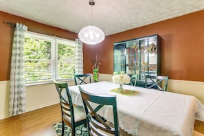 A dining area with a table set for four, surrounded by chairs, a chandelier, and a cabinet with glass doors. - 7 Mi to Stone Mtn Park! Spacious Family Getaway (Lilburn)