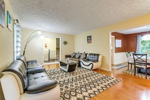 A living room with a sectional sofa, a coffee table, and a dining area with a table and chairs. - 7 Mi to Stone Mtn Park! Spacious Family Getaway (Lilburn)