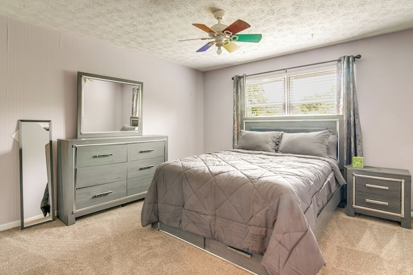 A bedroom with a bed, a dresser, a nightstand, a ceiling fan, and a window with curtains. - 7 Mi to Stone Mtn Park! Spacious Family Getaway (Lilburn)