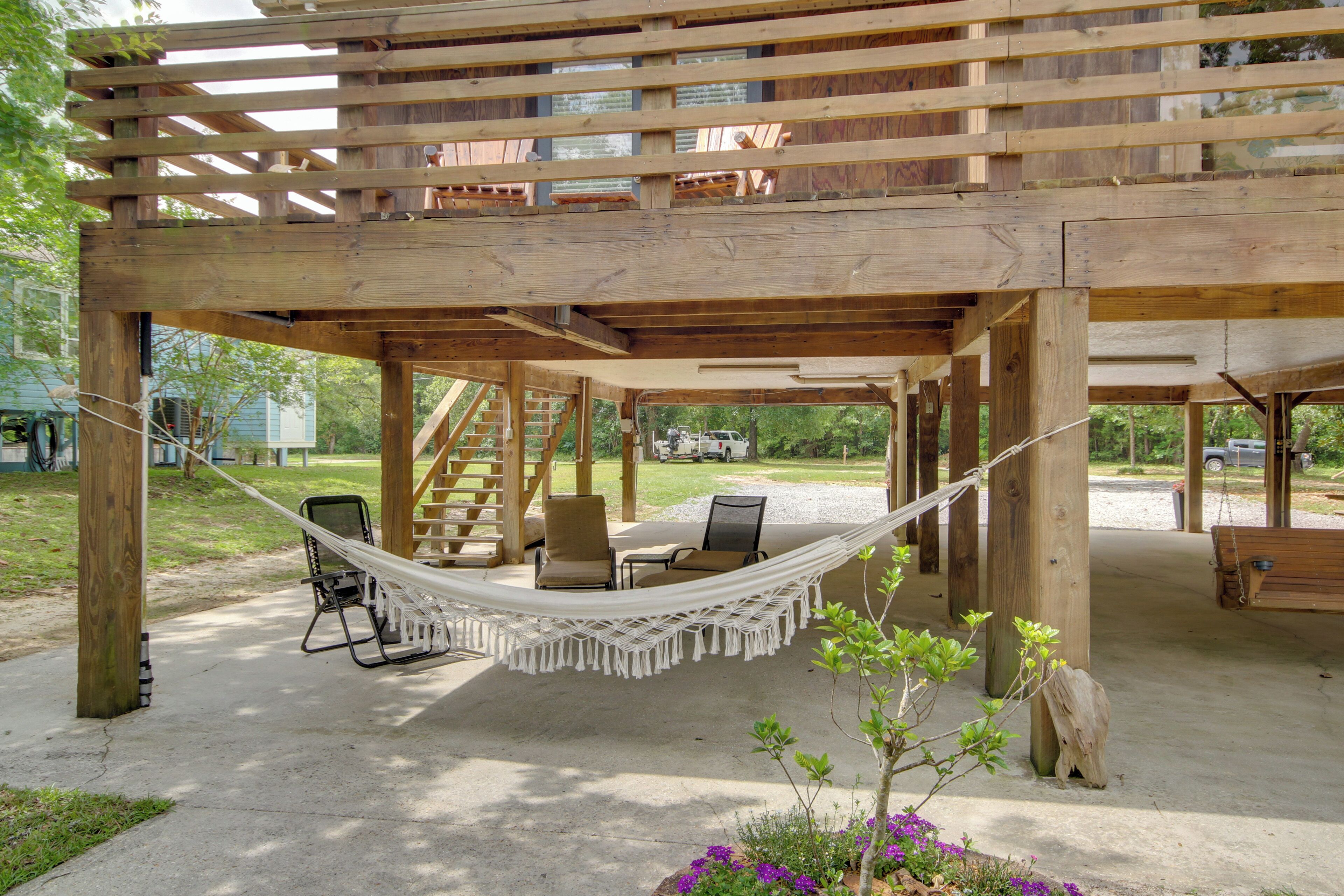 Une terrasse en bois avec un hamac, des chaises et un banc.