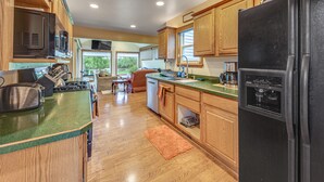 A kitchen with wooden cabinets, a black refrigerator, a microwave, and a stove. - Fall Escape! Waterfront Chain O'lakes Hideaway (Spring Grove)
