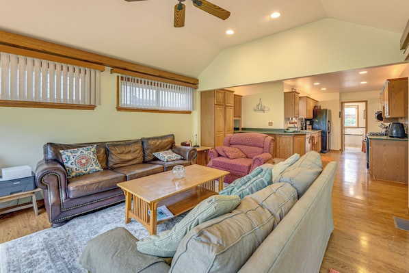 A spacious living room with a leather sofa, a wooden coffee table, and a large window with blinds.