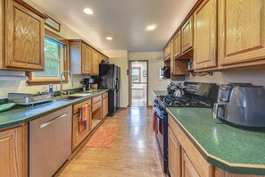 A kitchen with wooden cabinets, a stainless steel refrigerator, a stove, and a microwave.