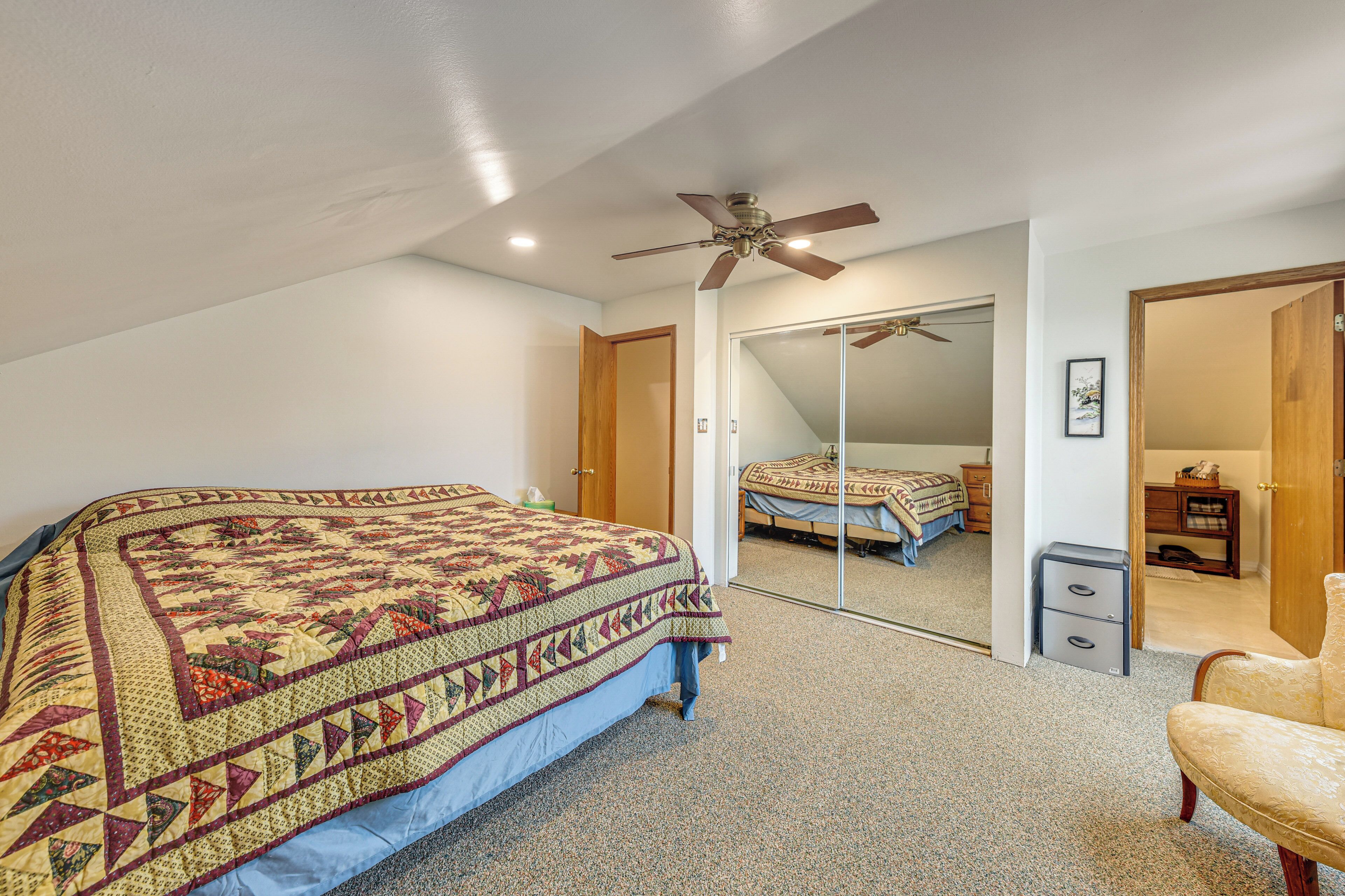 A bedroom with a bed, a ceiling fan, a wardrobe, and a nightstand.