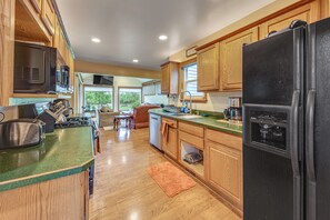 A kitchen with wooden cabinets, a black refrigerator, a microwave, and a stove.