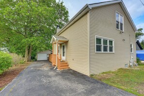 A two-story house with a front porch, a garage, and a large tree in the background.