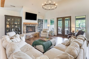 A spacious living room with a fireplace, large sofa, and a television mounted on the wall.