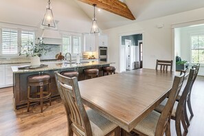 A spacious kitchen with a large island, wooden chairs, and pendant lighting.