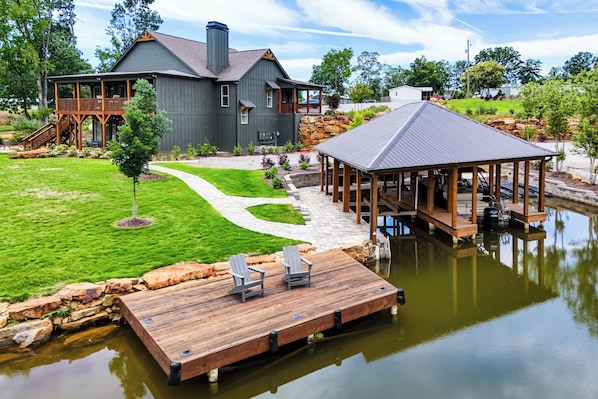 A house with a dock, a pond, and a stone wall.