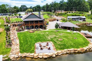 A lodge with a large deck, a pond, and a well-maintained lawn.