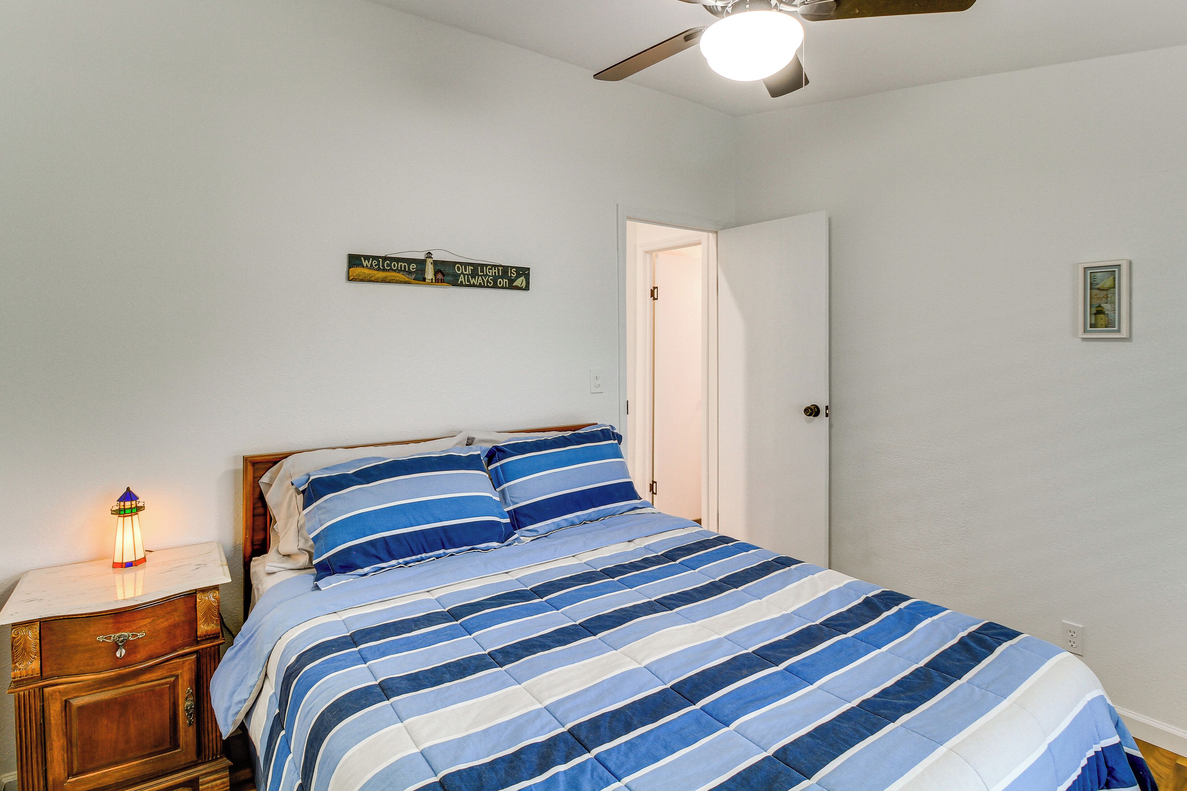 Un dormitorio con cama, mesita de noche y un cartel en la pared.